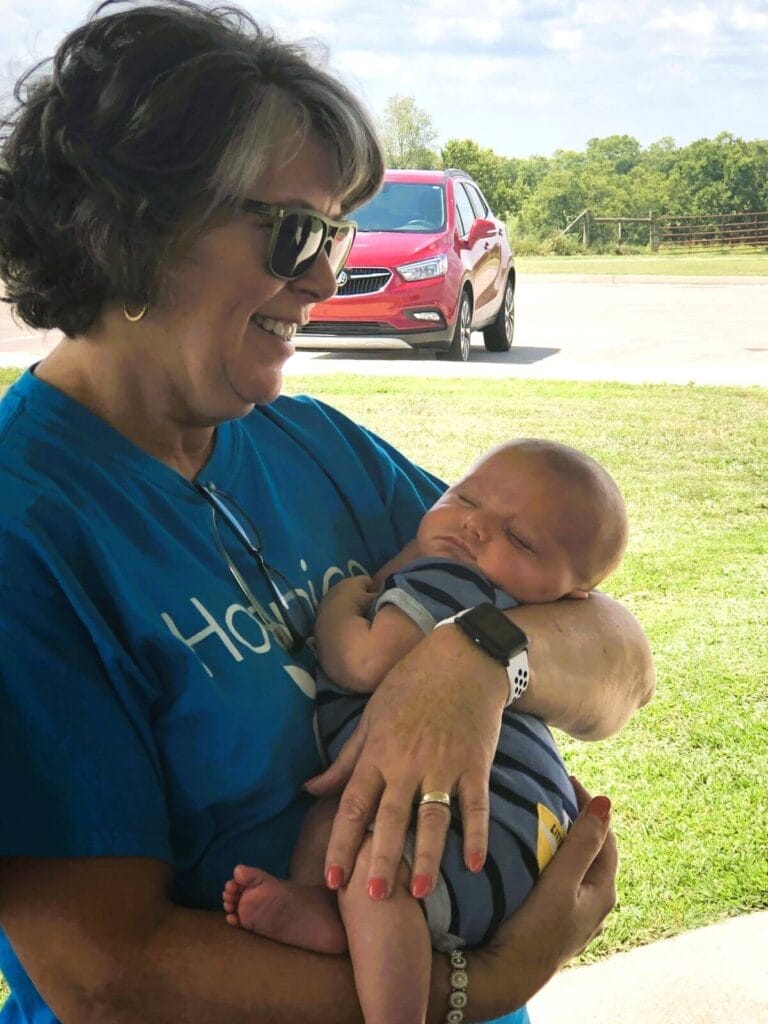 Donna Tapley holds infant at 2019 staff picnic.